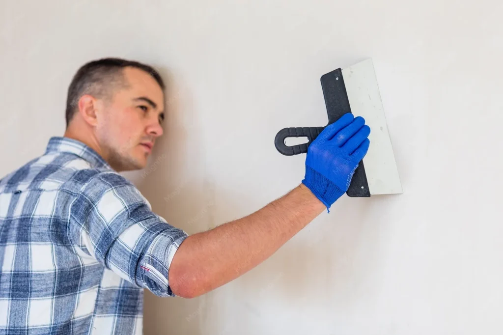 Afbouw en stukadoors: vakman met spaan bij een strak afgewerkte wand