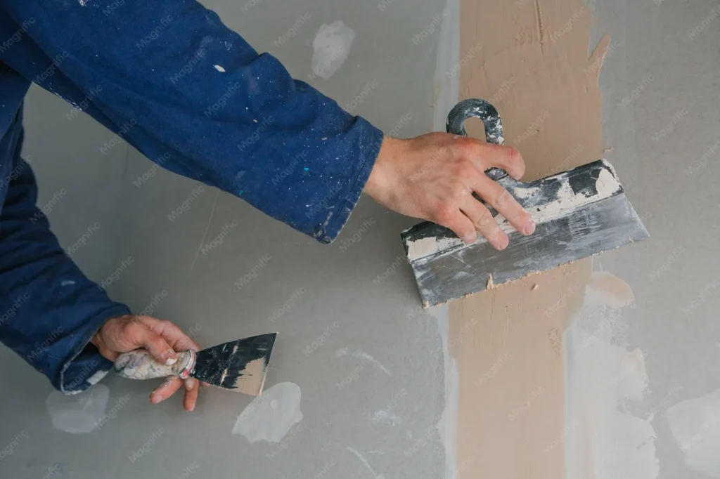 Afbouw en stukadoors: stukadoor werkt met twee spanen aan een strakke wand