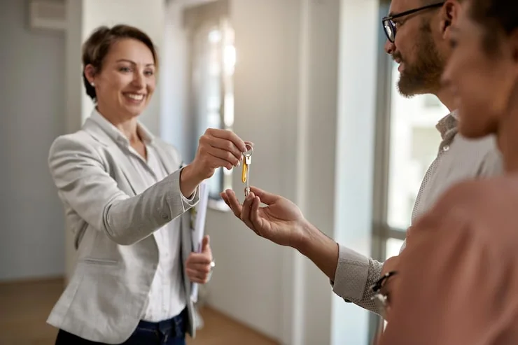 Makelaars overhandigen de sleutels van een nieuwe woning aan kopers