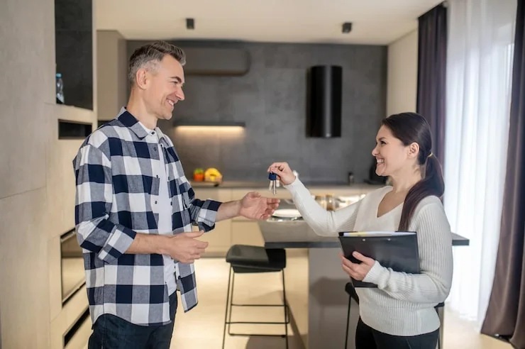 Makelaar overhandigt de sleutel van een nieuwe woning aan een koper